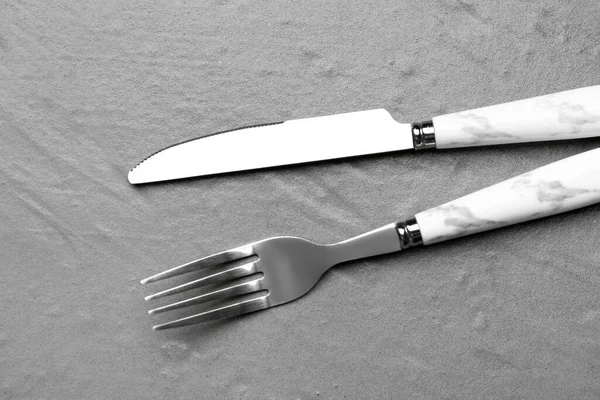 質感グレーの背景にプラスチックハンドル付きステンレス製のフォークとナイフ — ストック写真