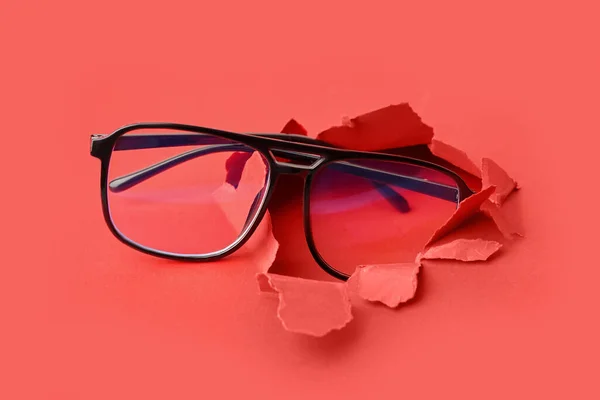 Stylowe Okulary Widoczne Przez Podarty Papier Czerwonym Tle — Zdjęcie stockowe