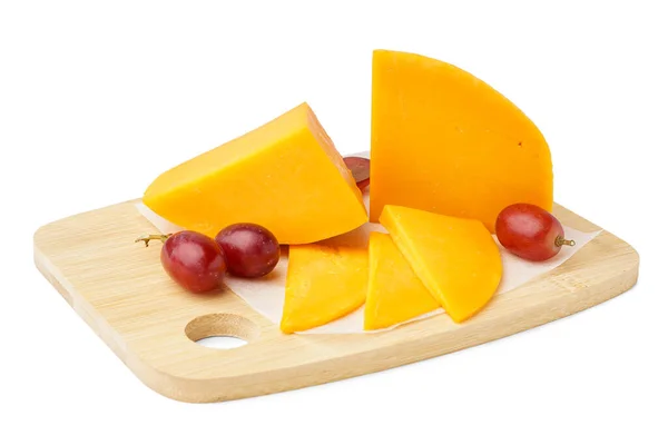 白い背景においしいチェダーチーズとブドウの破片でボード — ストック写真