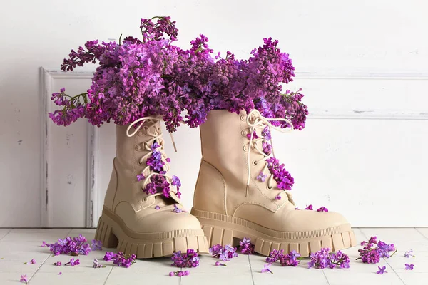 Şık kadın ayakkabıları ve açık duvarın yanında güzel leylak çiçekleri olan kompozisyon