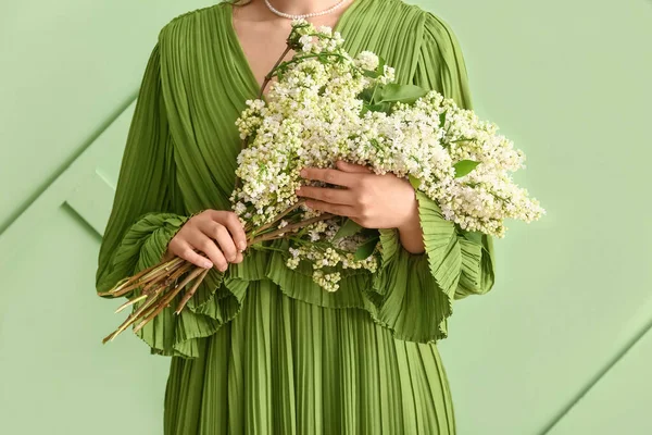 stock image Young woman with bouquet of lilac flowers on green background