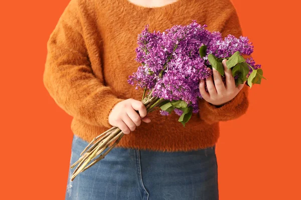 stock image Young woman with bouquet of lilac flowers on red background