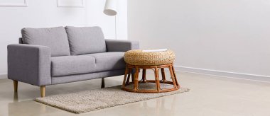 Hasır pouf ve ışık odasında halı olan gri kanepe. Tasarım için pankart