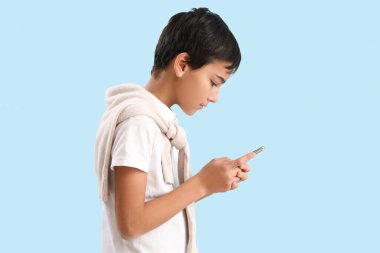 Little boy using mobile phone on blue background