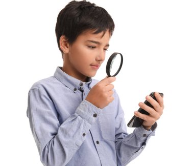 Little boy with magnifier and mobile phone on white background