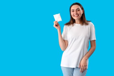 Young woman with menstrual pad on blue background