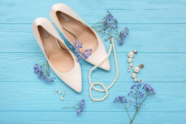 Şık kadın aksesuarları, topuklu ayakkabıları ve renkli ahşap arka planda çingene çiçekleri olan kompozisyon