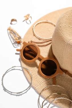 Güneş gözlüklü mücevherler ve beyaz arka planda yaz şapkası, yakın plan.