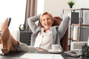 Olgun iş kadını ofisinde dinleniyor.