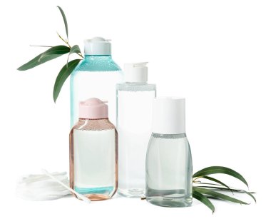Beyaz arka planda su şişeleri, pamuk tomurcukları, ped ve bitki dalları