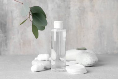 Pamuk yastıklı, toplu ve gri masadaki spa taşlı bir şişe mikiler suyu.