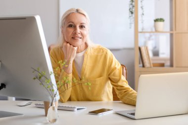 Masada dizüstü bilgisayarla çalışan olgun bir kadın programcı.