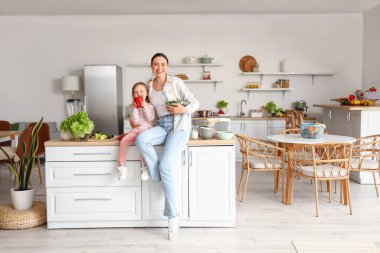 Annesiyle küçük bir kız ve mutfakta sağlıklı bir salata.