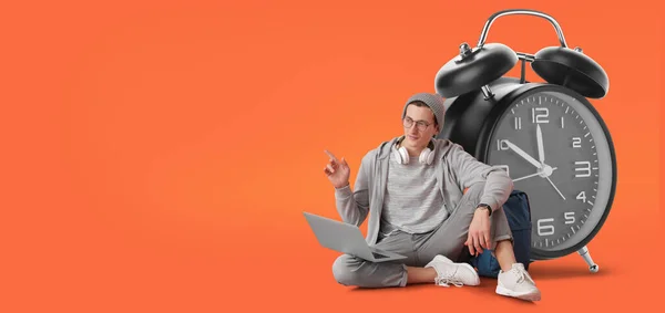 Männlicher Student Mit Laptop Und Großem Wecker Auf Orangefarbenem Hintergrund — Stockfoto
