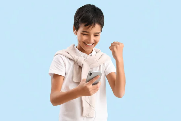Szczęśliwy Chłopiec Słuchawkach Pomocą Telefonu Komórkowego Niebieskim Tle — Zdjęcie stockowe