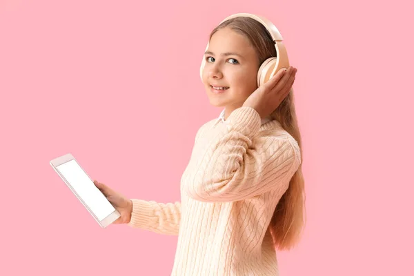 Kulaklıklı Pembe Arka Planda Tablet Bilgisayarı Olan Küçük Bir Kız — Stok fotoğraf