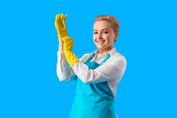 Młoda Kobieta Zakładająca Gumowe Rękawiczki Niebieskie Tło — Zdjęcie stockowe