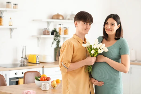 Mladý Muž Dává Tulipány Své Těhotné Ženě Kuchyni — Stock fotografie