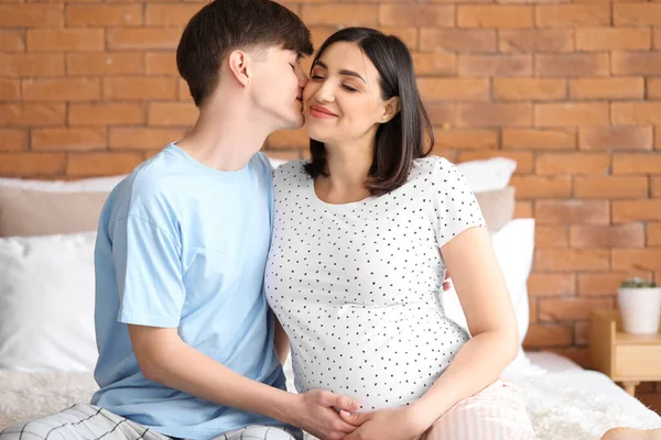 年轻的怀孕夫妇坐在卧室里 — 图库照片
