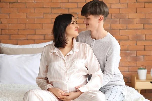 年轻的怀孕夫妇坐在卧室里 — 图库照片