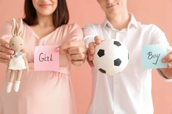 Young Pregnant Couple Holding Toys Papers Sex Baby Pink Background — Stock Photo, Image