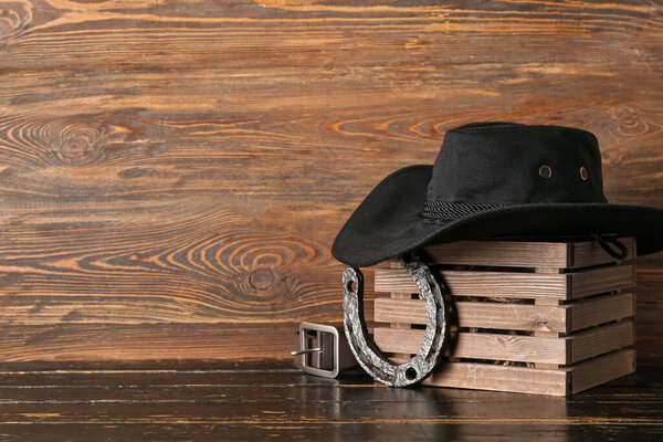 Cowboy hat, horseshoe and belt on wooden background
