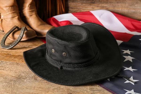 stock image Cowboy hat, boots and flag of USA on wooden background