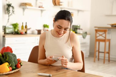 Evde glukometre kullanan genç diyabetik kadın.