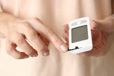 Olgun diyabetik kadın kan şekeri seviyesini glukometreyle ölçüyor.