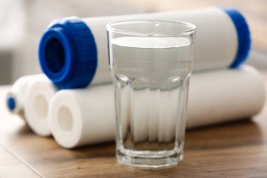 Mutfaktaki ahşap masada filtreli bir bardak su.