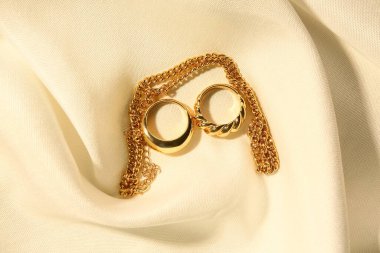 Güzel zincir kolye ve beyaz kumaş arka planda yüzükler