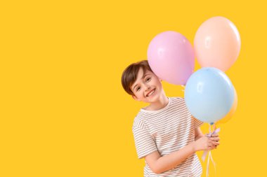 Sarı arka planda balonları olan küçük bir çocuk. Çocuk Bayramı kutlaması