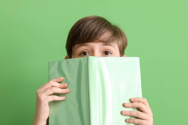 Yeşil arka plan üzerine kitabı olan küçük bir çocuk, yakın plan. Çocuk Bayramı kutlaması