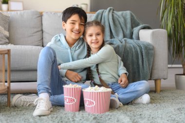 Küçük kız evde film izlerken kardeşine sarılıyor.