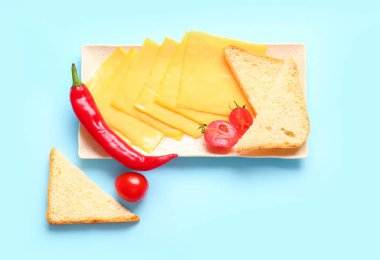 Lezzetli işlenmiş peynir tabağı. Mavi arka planda ekmek ve sebzeler.