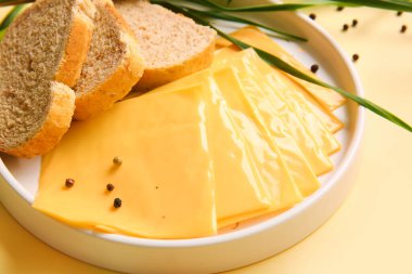 Turuncu arka planda ekmek ve soğanlı lezzetli işlenmiş peynir tabağı.