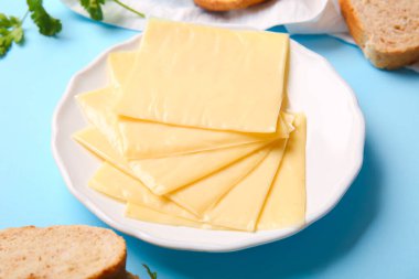 Lezzetli işlenmiş peynir tabağı ve mavi arka planda ekmek.