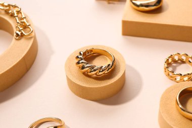 Bej arka planda yüzükler ve bileziklerle dekoratif podyumlar
