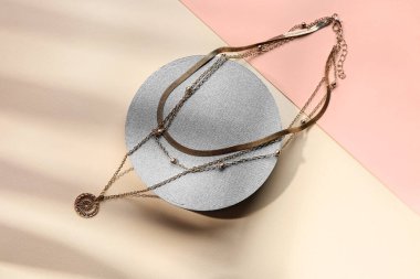 Arkaplanda gümüş kolyeler bulunan dekoratif podyumlar