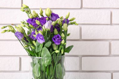 Beyaz tuğla arka planda Eustoma çiçekleri olan vazo