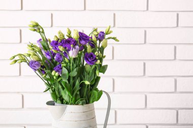 Beyaz tuğla arka planda Eustoma çiçekleri olan sürahi.