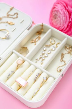 Pembe arka planda şık mücevherleri ve çiçekleri olan bir organizatör