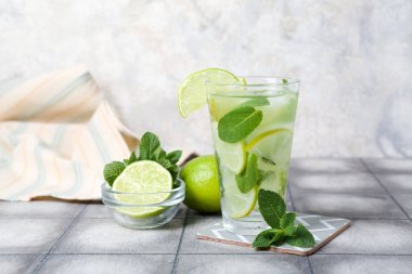 Masada bir bardak soğuk mojito ve malzemeler var.