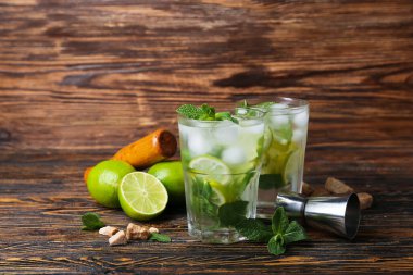 Soğuk mojito bardakları ve ahşap arka planda malzemeler.