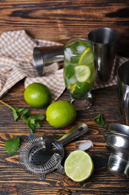Bir bardak soğuk mojito ve ahşap arka planda malzemeler.