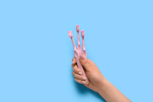 Vrouwelijke Hand Met Tandenborstels Blauwe Achtergrond — Stockfoto