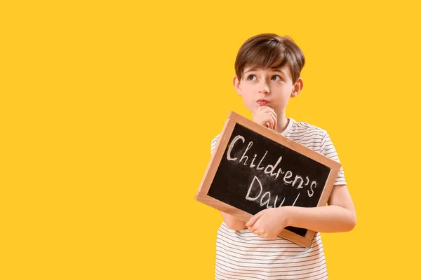 Thoughtful Little Boy Holding Chalkboard Text Children Day Yellow Background — Stock Photo, Image
