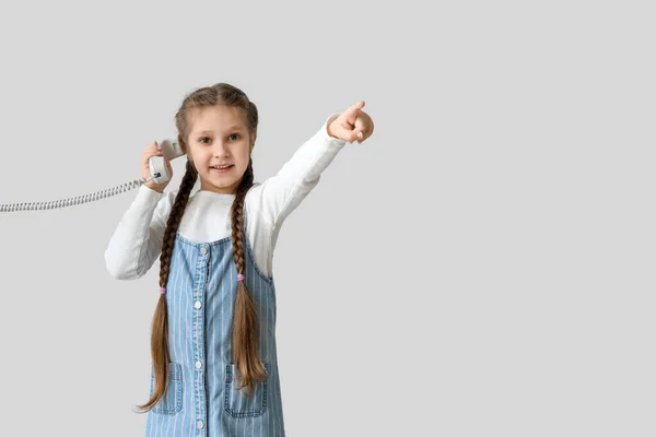 Little Girl Phone Receiver Pointing Something Light Background Children Day — Stock Photo, Image