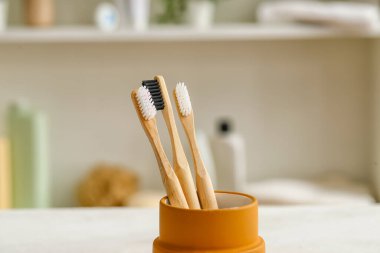 Odadaki beyaz masanın üzerinde bambu diş fırçası tutucusu.