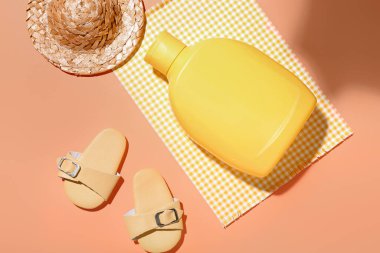 Turuncu arka planda güneş kremi ve plaj aksesuarları ile yaratıcı kompozisyon